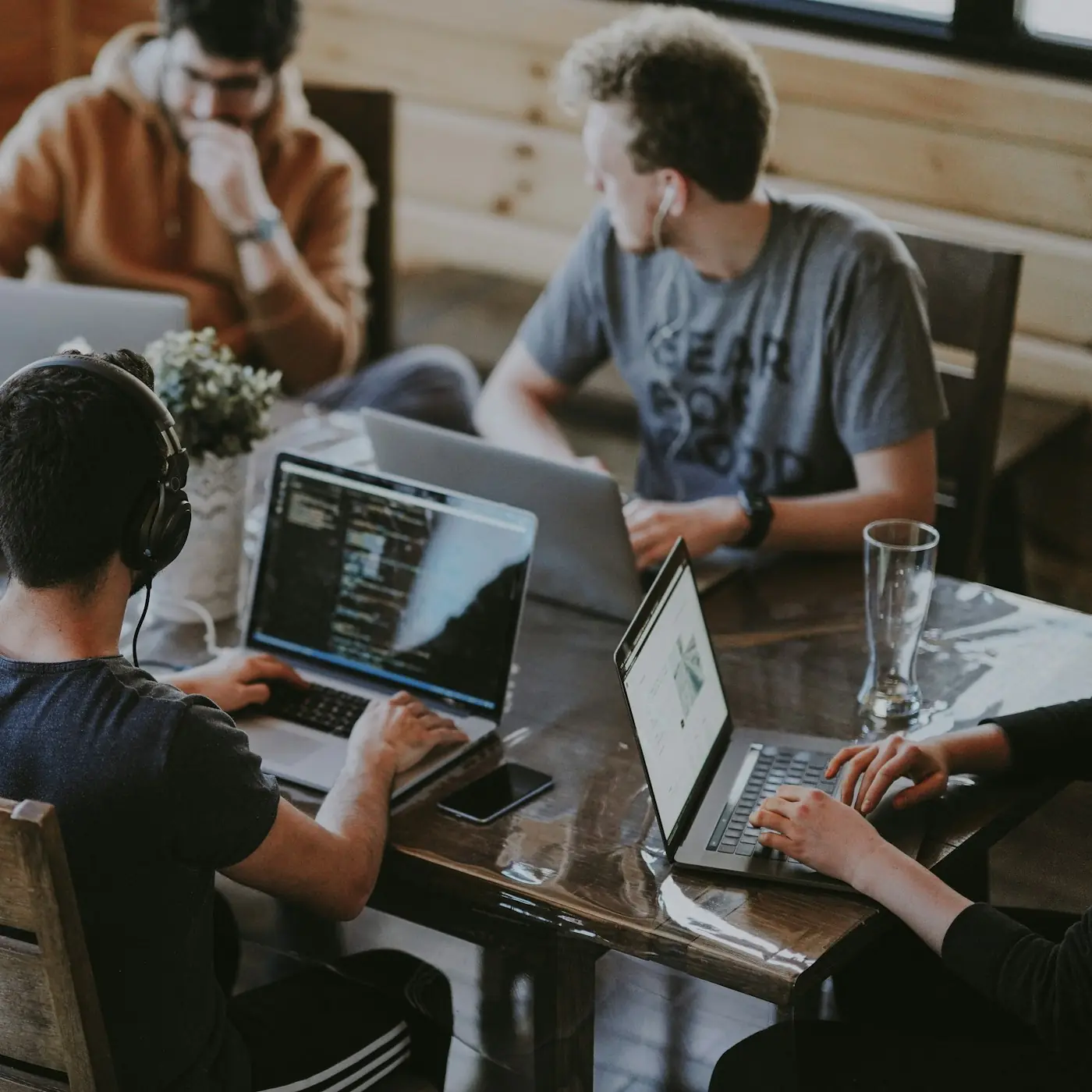 A small team working on laptops around a wooden table