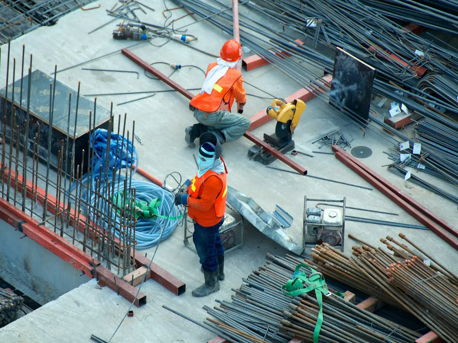 Construction crew in safety vests working among steel rebar on a site