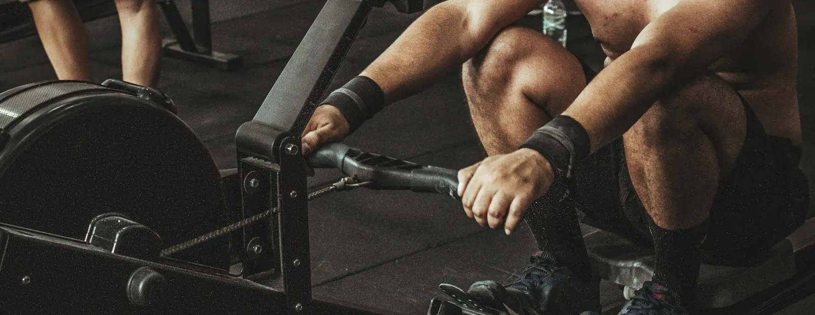 A rower pulling hard on an indoor rowing machine